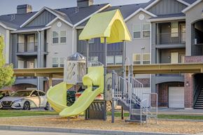 Farmington apartment for rent - a playground with a yellow slide in front of an apartment building