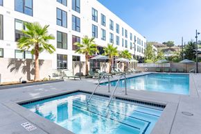 Los Angeles apartment for rent - A pool in front of a building with palm trees.