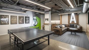 A ping pong table is in the middle of a room with a couch and a coffee table.