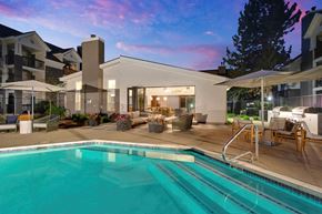 Englewood apartment for rent - A swimming pool in front of a modern building with a sunset in the background.