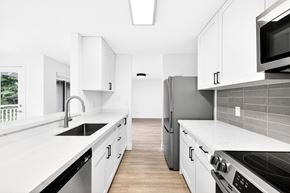 Bainbridge Island apartment for rent - A kitchen with white cabinets and a black refrigerator.