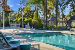 Escondido apartment for rent - A pool surrounded by trees and chairs.