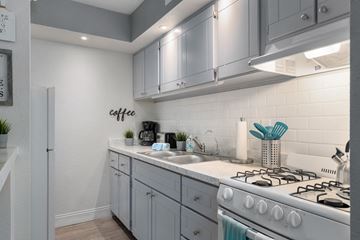 Phoenix apartment for rent - A modern kitchen with a white stove and grey cabinets.