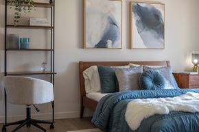 Vancouver apartment for rent - A bedroom with a bed, chair, and two paintings on the wall.