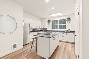 Renton apartment for rent - A modern kitchen with white cabinets and a wooden floor.