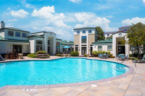 San Mateo apartment for rent - A swimming pool surrounded by a patio with chairs and a building in the background.