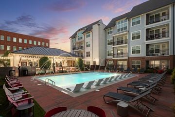 Norcross apartment for rent - A swimming pool surrounded by lounge chairs and umbrellas in front of a building.
