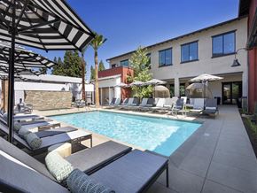 Montclair apartment for rent - A pool with sun loungers and umbrellas in front of a building.