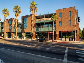 Santa Monica apartment for rent - a street view of two brick buildings with palm trees in front of them