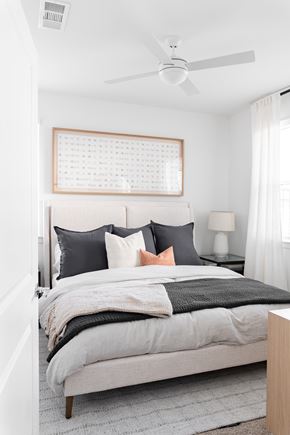 Austin apartment for rent - A bedroom with a bed, pillows, a fan, and a window.