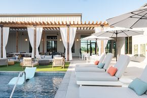 Austin apartment for rent - A poolside lounge area with white cushioned chairs and umbrellas.