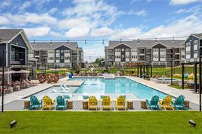 Greeley apartment for rent - an outdoor pool with yellow and blue chairs around it and apartments in the background