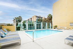 Marina Del Rey apartment for rent - A pool surrounded by sun loungers and a yellow wall.