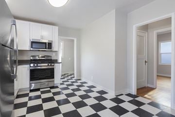 San Leandro apartment for rent - A black and white checkered floor in a kitchen with a refrigerator, microwave, oven, and stove.