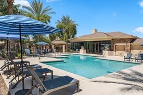 Phoenix apartment for rent - A pool area with a blue umbrella and lounge chairs.