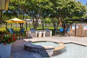 Copperas Cove apartment for rent - A small hot tub sits in the middle of a patio surrounded by chairs and a yellow umbrella at Clear Creek Meadows Apartments, Texas