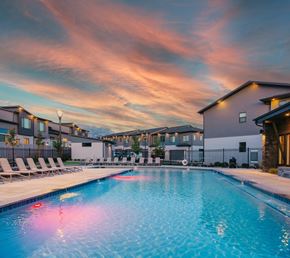 Pleasant Grove townhouse for rent - A swimming pool surrounded by lounge chairs and buildings under a colorful sky.