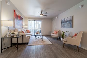 Phoenix apartment for rent - A living room with a white couch, a chair, and a table with a vase on it.
