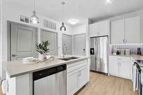 Decatur apartment for rent - A modern kitchen with white cabinets and a wooden floor.