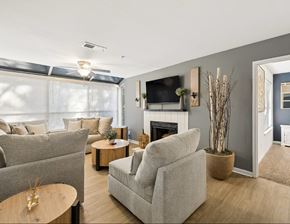 Kennesaw apartment for rent - A living room with a grey couch, a white armchair, a wooden coffee table, and a fireplace.