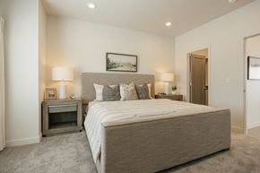 South Jordan townhouse for rent - Large bed and nightstands in a model unit at Rise townhomes for rent in South Jordan, Utah.