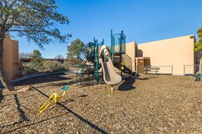 Albuquerque apartment for rent - A playground with a yellow seesaw and a green slide.