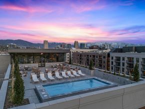Salt Lake City apartment for rent - A rooftop pool area with lounge chairs and a view of the city skyline at sunset.