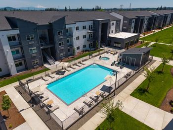 A swimming pool surrounded by lounge chairs and apartment buildings in the background.