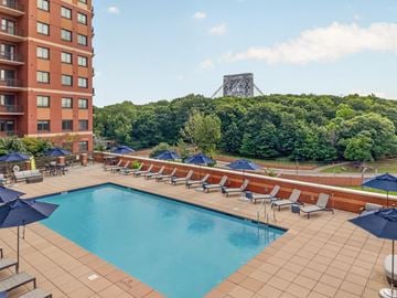 Fort Lee apartment for rent - A large swimming pool surrounded by lounge chairs and umbrellas.