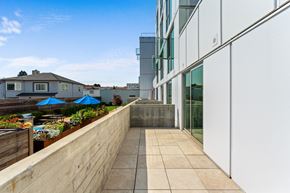 Oakland apartment for rent - a balcony with a stone wall and a glass building