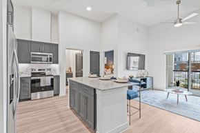 Denton apartment for rent - A modern kitchen with a large island and a refrigerator on the left.