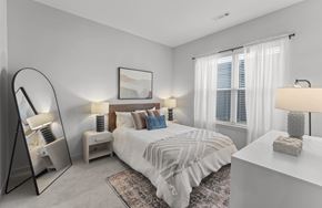 Warwick apartment for rent - A bedroom with a large bed, a side table with a lamp, and a mirror.