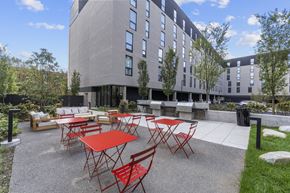 Philadelphia apartment for rent - A modern building with a patio area featuring red chairs and tables.