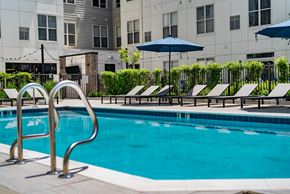 Hackensack apartment for rent - A pool with a diving board and lounge chairs.
