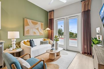 Dallas apartment for rent - A well-lit living room with a white sofa, a wooden coffee table, and a television on the wall.