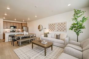 Fort Collins apartment for rent - Model living room and kitchen at Bloom Rental Living apartments in Fort Collins, CO, featuring wood grain floor paneling.
