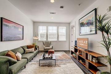 Greeley apartment for rent - A living room with a green couch, a coffee table, and a painting on the wall.