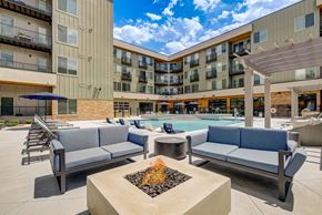 Colorado Springs apartment for rent - a patio with couches and a fire pit with a pool in the background