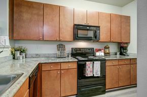 Baton Rouge apartment for rent - A kitchen with brown cabinets and a black stove top oven.