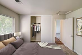 Concord apartment for rent - A bedroom with a large bed and a closet with clothes hanging.