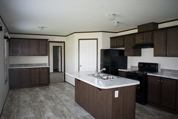 Williston apartment for rent - A kitchen with brown cabinets and a black refrigerator.