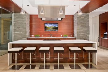 A modern kitchen with a bar area and a television above the island.