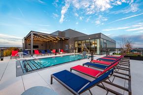 Washington apartment for rent - a pool with red and blue lounge chairs in front of a building