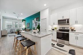 Austin apartment for rent - a kitchen with white cabinets and a large island with bar stools