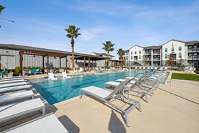 Bastrop apartment for rent - a swimming pool with lounge chairs at the resort on a sunny day