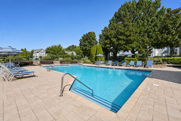 Charlotte apartment for rent - A swimming pool surrounded by a brick patio and lounge chairs.