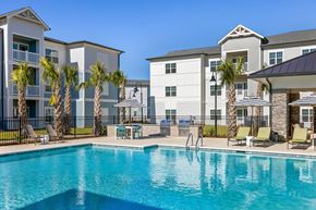 Ladson apartment for rent - A swimming pool in front of a building with palm trees.