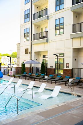 Charlotte apartment for rent - A pool area with chairs and a building in the background.