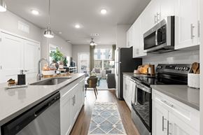 Charlotte apartment for rent - A modern kitchen with white cabinets and black appliances.