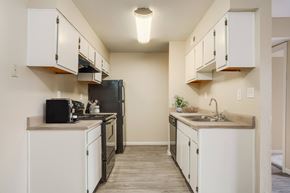 Rio Rancho apartment for rent - A kitchen with white cabinets and a black refrigerator.